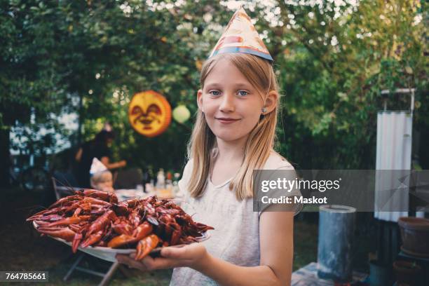 portrait of girl holding plate with cooked crayfish at garden dinner party - crawfish stockfoto's en -beelden