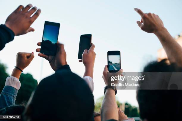 low angle view of friends photographing from smart phones against sky - taking photo with phone stock pictures, royalty-free photos & images