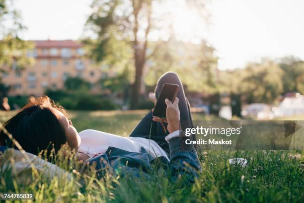 teenage girl using smart phone while lying on grass - laying park stock pictures, royalty-free photos & images