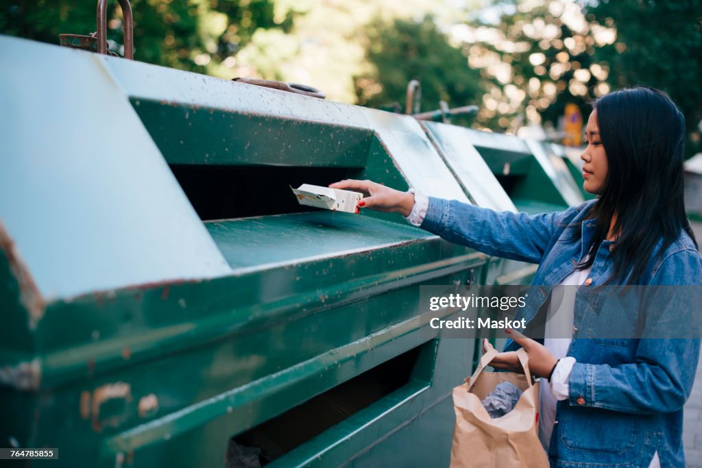 Teenage girl throwing packet in garbage can