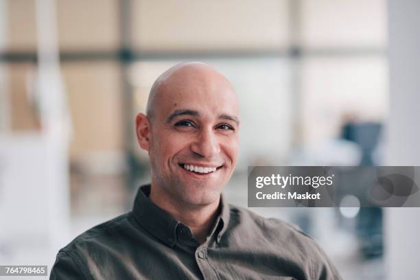portrait of smiling mature businessman sitting at office - onscherpe achtergrond stockfoto's en -beelden