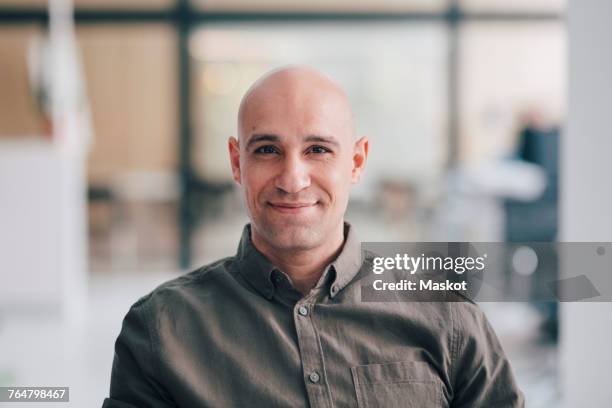 portrait of smiling bald mature businessman sitting at office - calvo fotografías e imágenes de stock