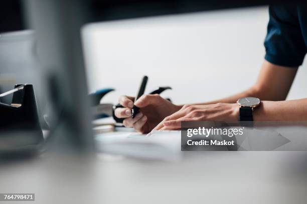 cropped image of businesswoman writing at desk in office - human role fotografías e imágenes de stock