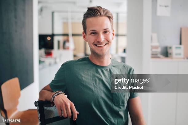 portrait of smiling confident young businessman sitting at office - 20s confident young male stock pictures, royalty-free photos & images