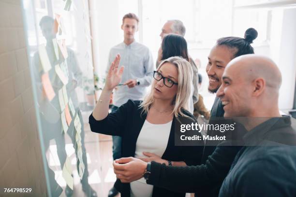 smiling business team looking at adhesive notes in board room during meeting - team looking at adhesive notes in board room during meeting stock-fotos und bilder