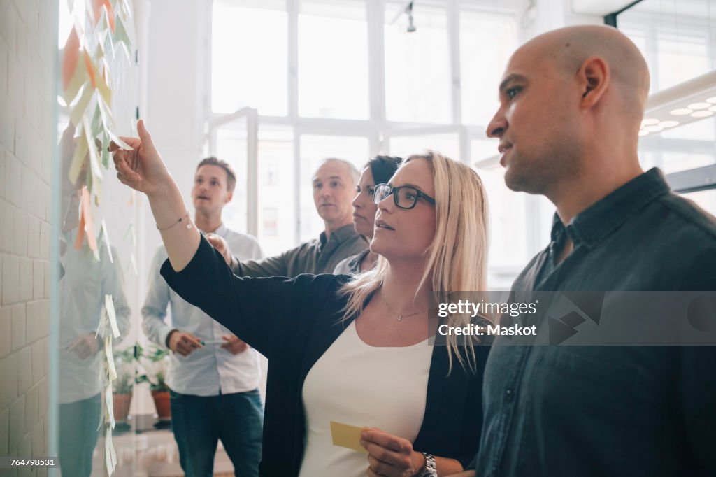 Business team looking at adhesive notes in board room during meeting