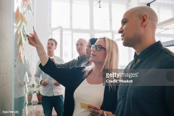business team looking at adhesive notes in board room during meeting - postit stockfoto's en -beelden