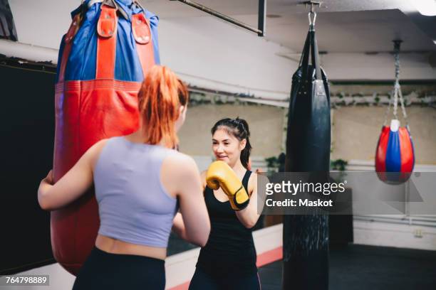 redhead woman training and female athlete with punching bag at health club - slaan met vuist stockfoto's en -beelden