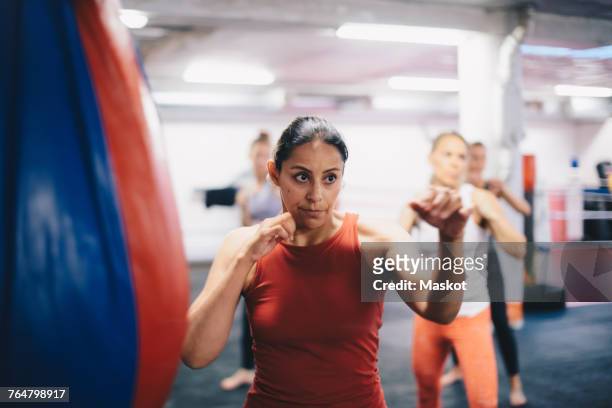 female instructor and athletes standing in fighting stance while practicing martial arts at gym - kick boxing fotografías e imágenes de stock