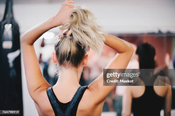 rear view of blond woman tying ponytail at gym - paardenstaart stockfoto's en -beelden