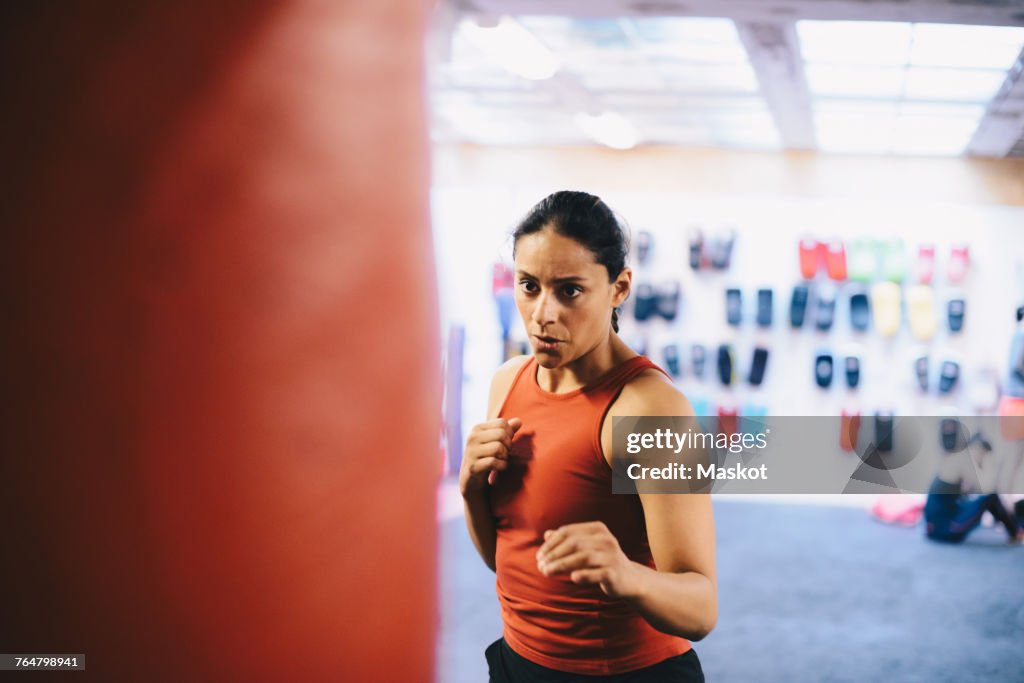 Dedicated female athlete looking at punching bag in health club