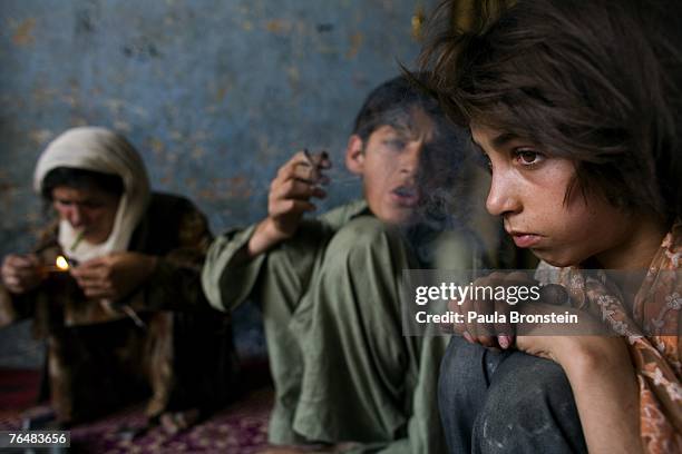 Zaher smokes heroin along side his mother Sabera and sister Gulparai August 27, 2007 in Kabul, Afghanistan. Zaher's mother, Sabera, a widow, has been...