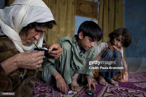 Sabera smokes heroin along side her children Zaher and Gulparai August 27, 2007 in Kabul, Afghanistan. Sabera, a widow, has been smoking for four...