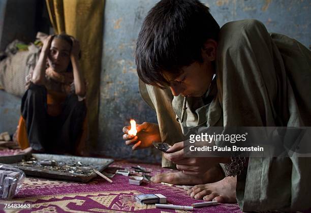 Zaher smokes heroin along side his mother Sabera and sister Gulparai August 27, 2007 in Kabul, Afghanistan. Zaher's mother, Sabera, a widow, has been...