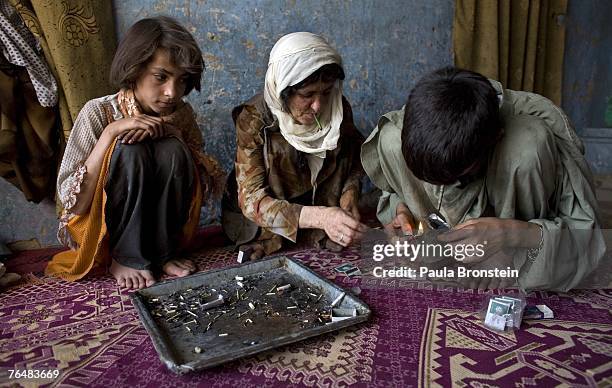 Zaher smokes heroin along side his mother Sabera and sister Gulparai August 27, 2007 in Kabul, Afghanistan. Zaher's mother, Sabera, a widow, has been...