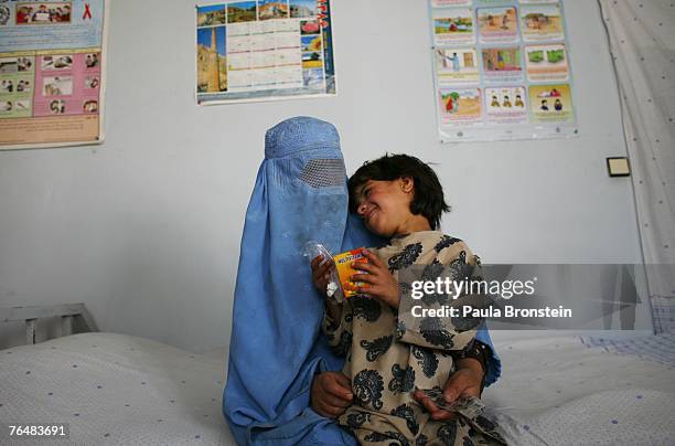 Former drug addict Habiba sits with her daughter, Farena holding medication that they received at the women's drop-in center at the New Life Center...