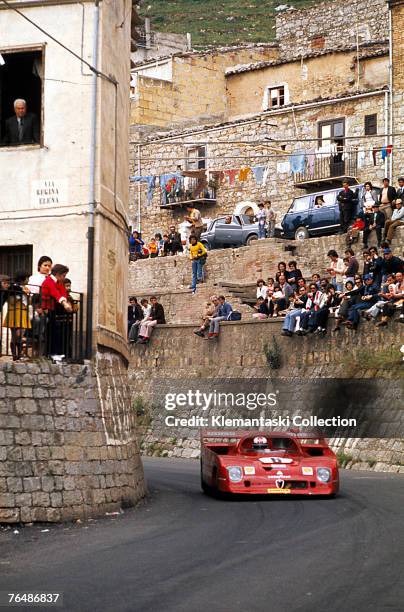 The works Alfa Romeo 33TT12, driven by Rolf Stommelen and Andrea de Adamich, rounds a village corner during the Targa Florio, Sicily, 13th May 1973....