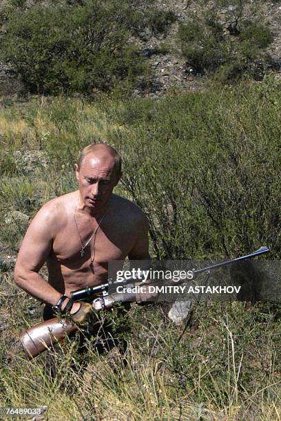 This pool picture provided 03 September 2007 shows Russian President Vladimir Putin carrying a hunting rifle in the Republic of Tuva, 15 August 2007....