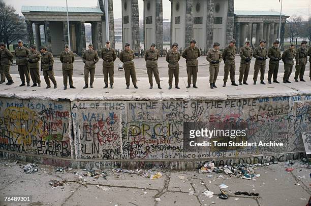 Soldiers guard the Berlin Wall on the day following its fall, with the Brandenburg Gate in the background, 10th November 1989. This is a high profile...