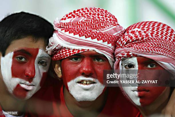 Bahraini fans with the colours of their national flag painted on their faces attend the Gulf Clubs Championship football match between Bahrain's...
