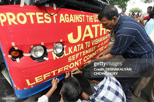 Indian Left activists attach a banner on a bus at the start of a 'Jatha' in Kolkata, 04 September 2007, against a massive joint naval exercise which...