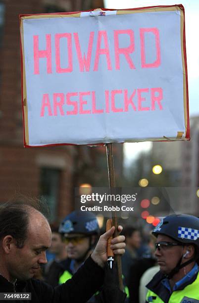 Protester holds a sign with a derogatory comment against Australian Prime Minister John Howard during "The Stop Bush Coalition" protest at the...