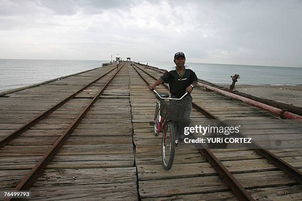 Local resident pushes his bike over an old jetty in the City port of La Ceiba, Honduras under a cloudy sky as hurricane Felix approaches 04 September...