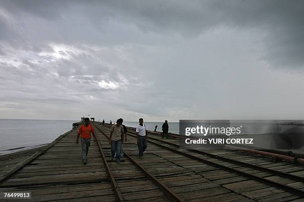Residents walk over an old jetty in the city port of La Ceiba, Honduras, under a cloudy sky as hurricane Felix approaches 04 September 200 7....