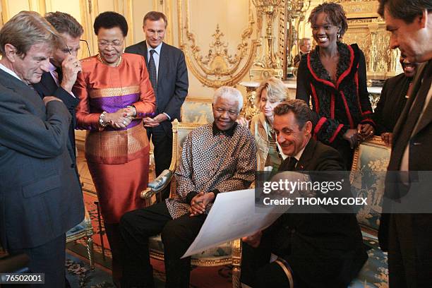 French President Nicolas Sarkozy shows off a photo offered by former South African president Nelson Mandela , as his wife Graca Machel, French...