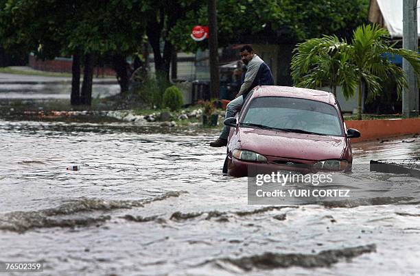 Man is sat on his car in a flooded street during heavy rains in the city port of La Ceiba, Honduras as hurricane Felix approaches 04 September 2007....