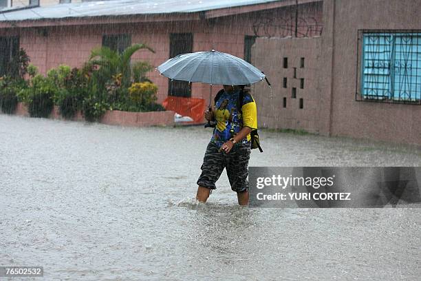 Woman crosses a flooded street under heavy rain in the City port of La Ceiba, Honduras as hurricane Felix approaches 04 September 2007. As hurricane...