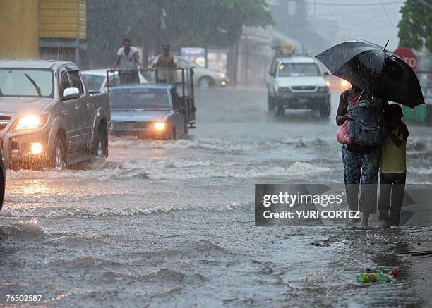 Woman walks with her son by a flooded street under heavy rain in the City port of La Ceiba, Honduras as hurricane Felix approaches 04 September 2007....