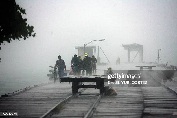 Group of fishermen leave an old jetty at the beach during heavy rain in the port of La Ceiba, Honduras as hurricane Felix approaches 04 September...