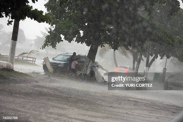 People take cover under a tree near during heavy rain and winds in the city port of La Ceiba, Honduras as hurricane Felix approaches 04 September...