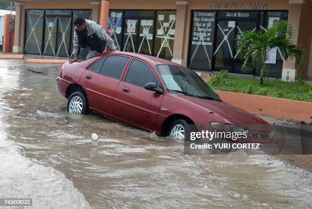 Driver climbs atop his car in a flooded street of the city port of La Ceiba, Honduras as hurricane Felix approaches 04 September 2007. As Hurricane...