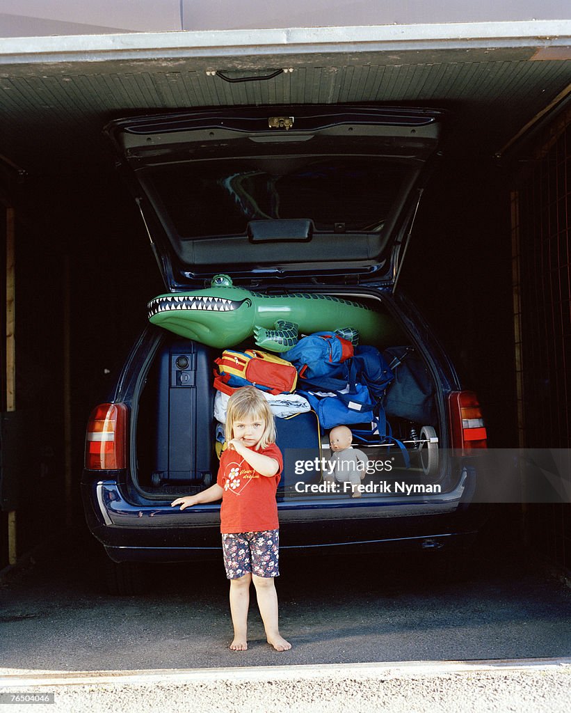 A girl in front of a crammed car.