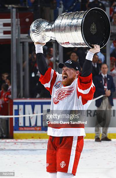 Kris Draper of the Detroit Red Wings raises the Stanley Cup after defeating the Carolina Hurricanes during game five of the NHL Stanley Cup Finals on...
