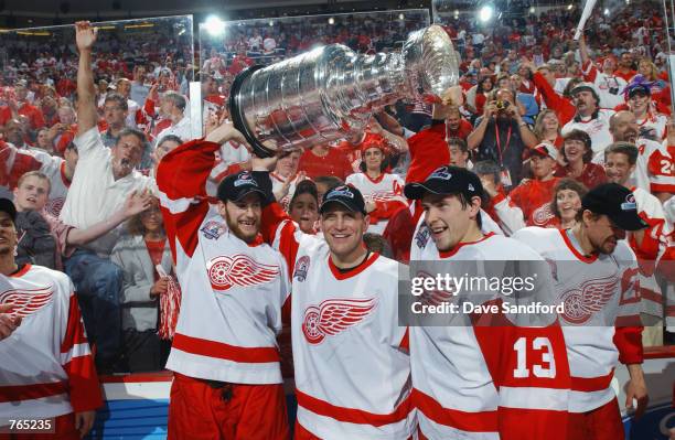 Boyd Devereaux , Brett Hull and Pavel Datsyuk of the Detroit Red Wings raise the Stanley Cup after defeating the Carolina Hurricanes during game five...