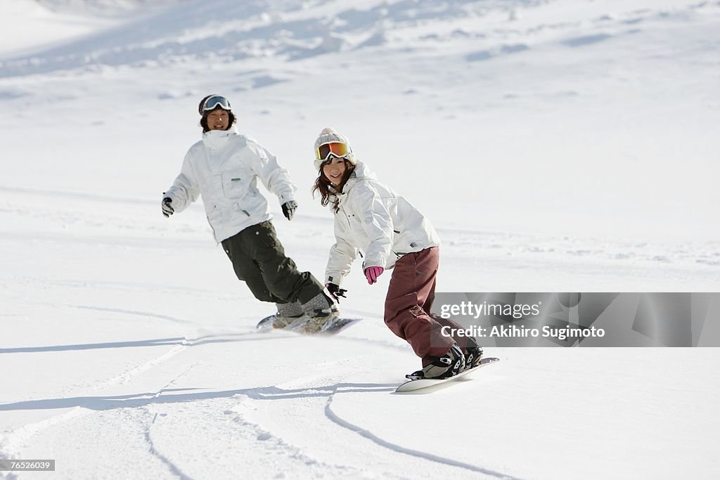 Two young Asian snowboarders in action