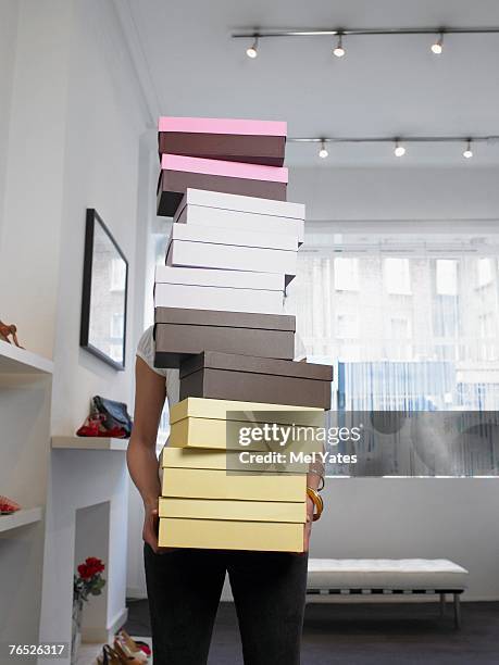 young woman holding pile of shoe boxes obscuring face - shoe box stock pictures, royalty-free photos & images
