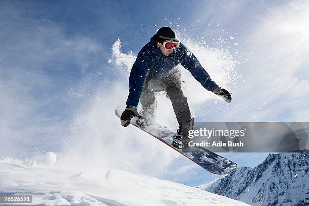 male snowboarding on mountain, action shot - tabla de snowboard fotografías e imágenes de stock