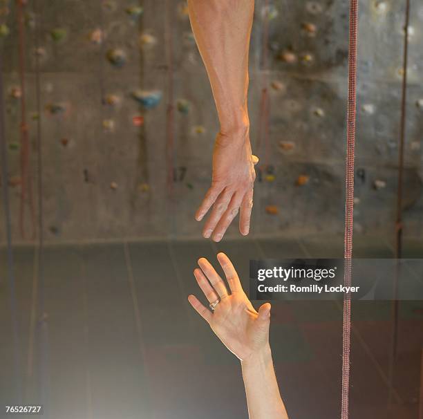 man and woman reaching hands together at climbing centre - 爬山繩 個照片及圖片檔