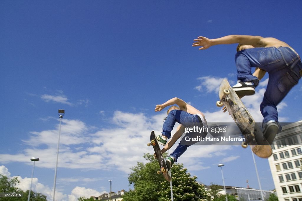 Skateboarders in mid-air, low angle view