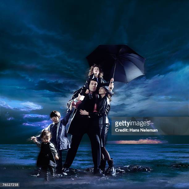 family with children with cloudscape in background - mother protecting from rain stockfoto's en -beelden