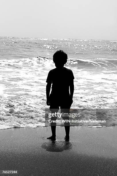 boy watching crashing waves, rear view - boy barefoot rear view stockfoto's en -beelden