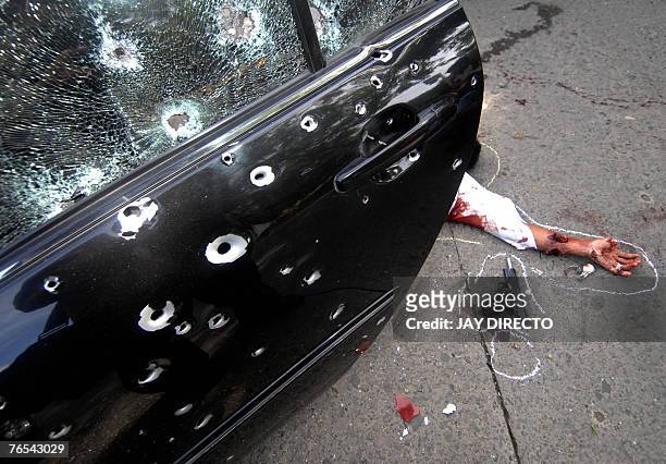 Bullet riddled car that was transporting four suspected car-jackers, with one dead victim slumped on the pavement, is seen beside the Philippine...