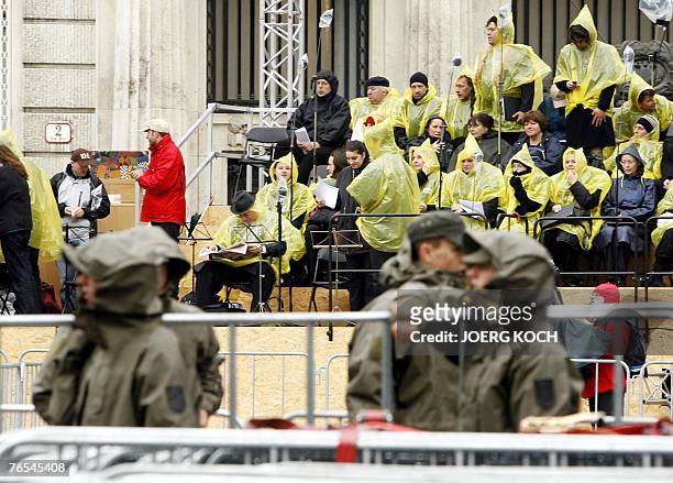 Members of the chorus hide under rain capes during rehearsals as Austrian soldiers set up barriers ahead of the visit of pope Benedict XVI, 06...