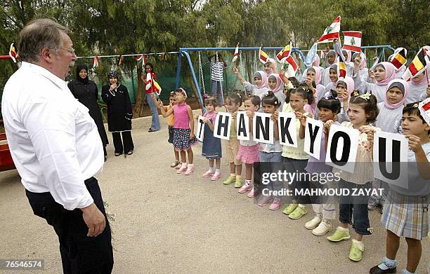 Belgian Defence Minister Andre Flahaut looks toward Lebanese orphans holding up printed letters spelling out the phrase "Thank You" during his visit...