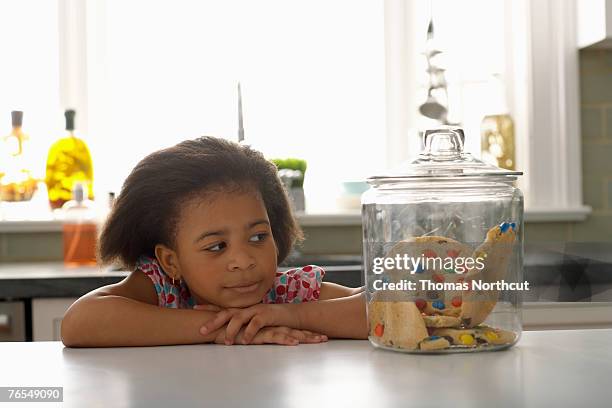 girl (4-6) looking at jar of cookies - candy jar stock pictures, royalty-free photos & images