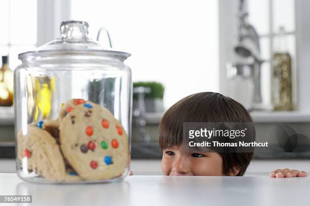 boy (3-5) looking at cookie jar on kitchen counter - child cookie jar stockfoto's en -beelden